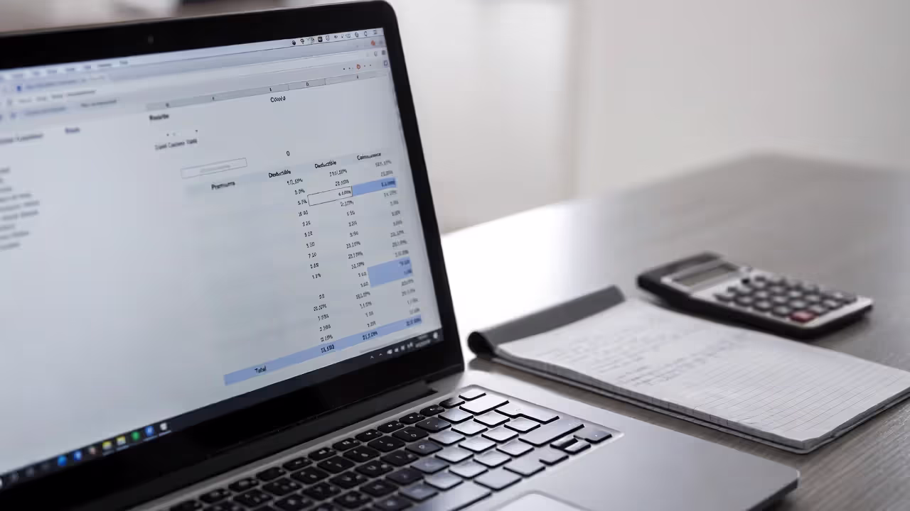 Pet insurance cost calculator on a laptop with a notebook and calculator beside it